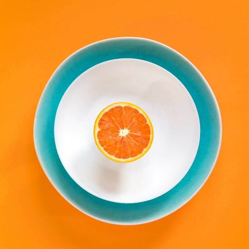 A single sliced orange in a blue and while bowl.