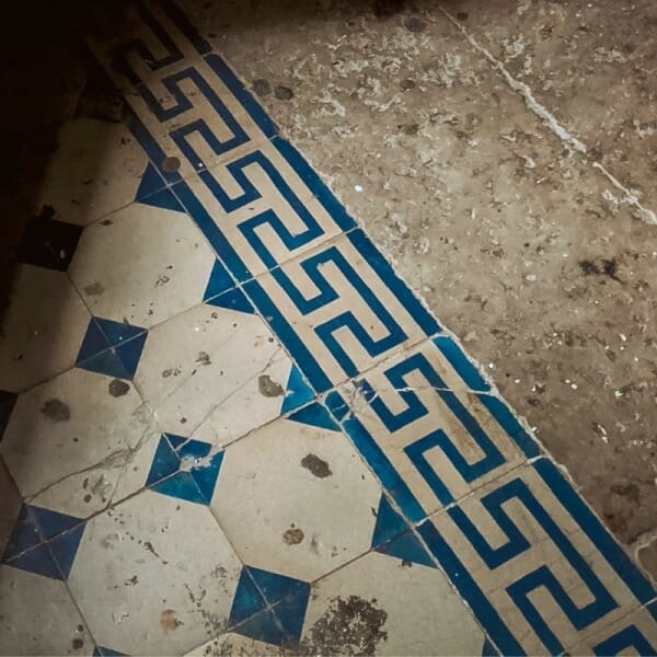 Blue and white floor tiles with meander motif on the border.