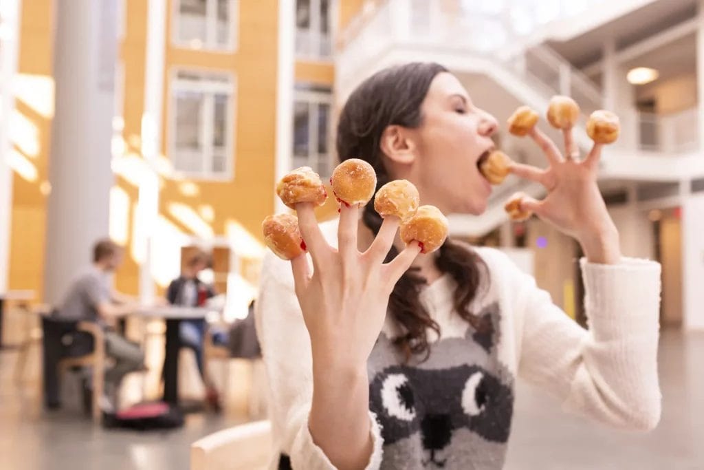 Free photos - lady feasting on donuts, with a donut stuck on each finger.