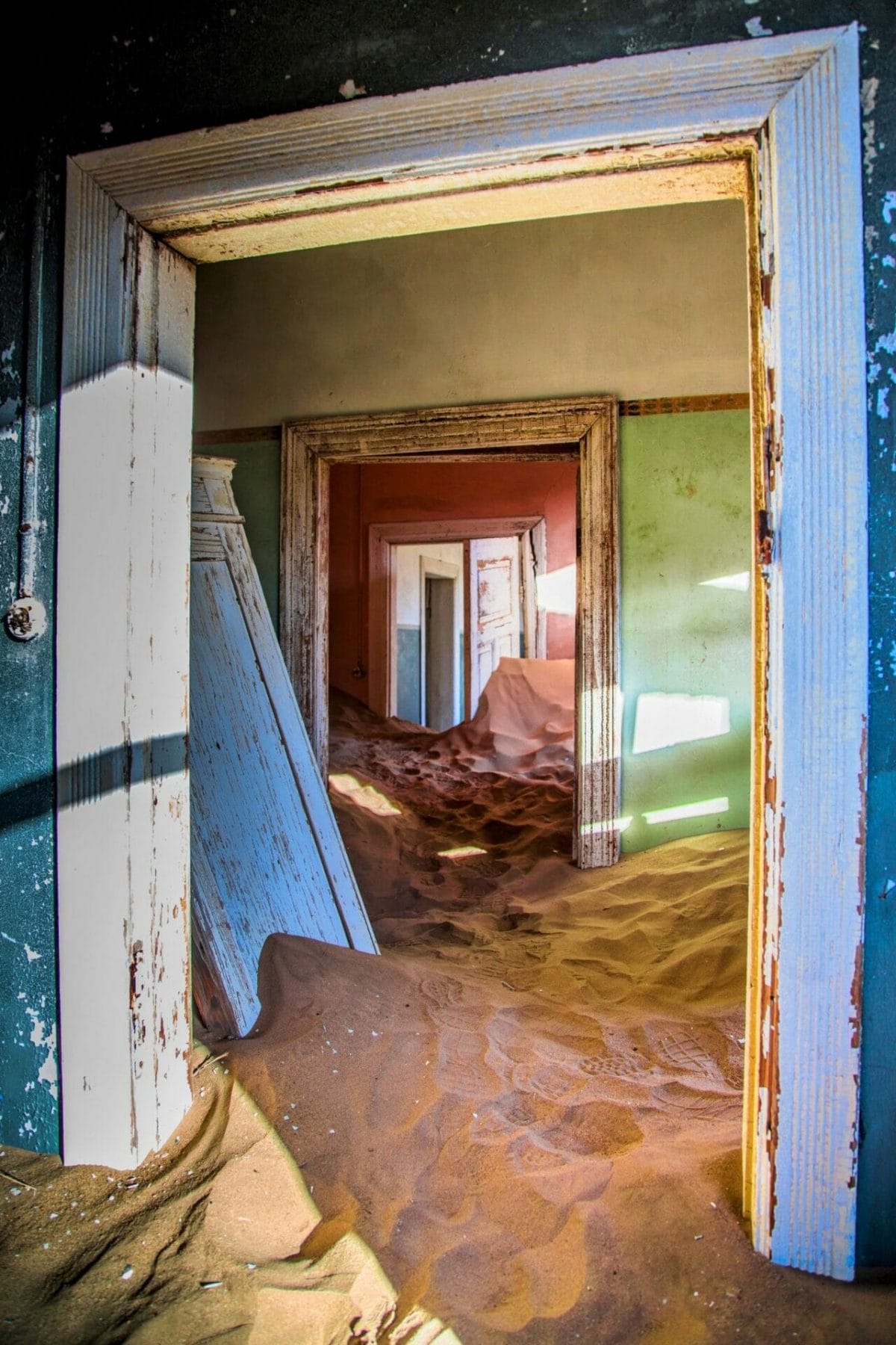 Another view of the sand filled house, looking through several doorways, with different colored rooms, and interesting play of light and shadows.